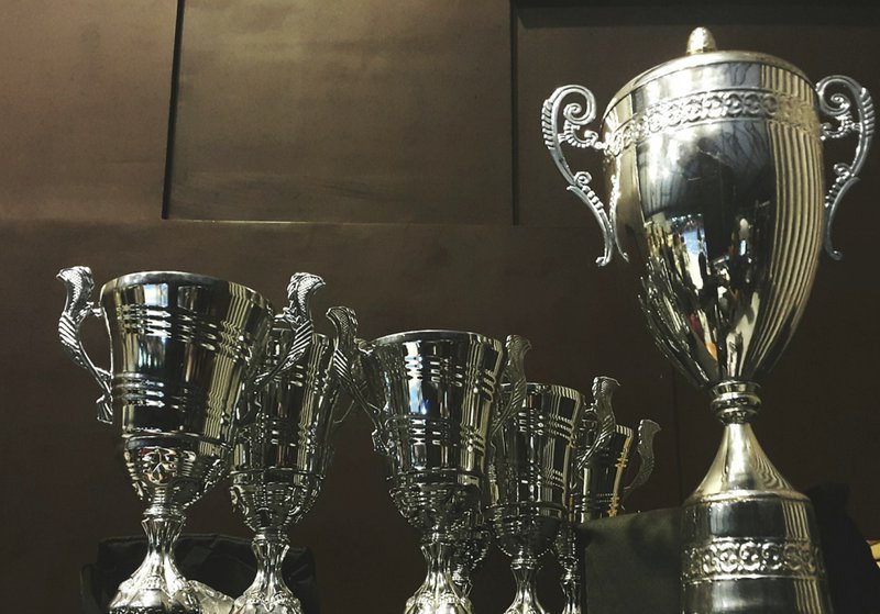 several silver and gold trophies on wooden surface