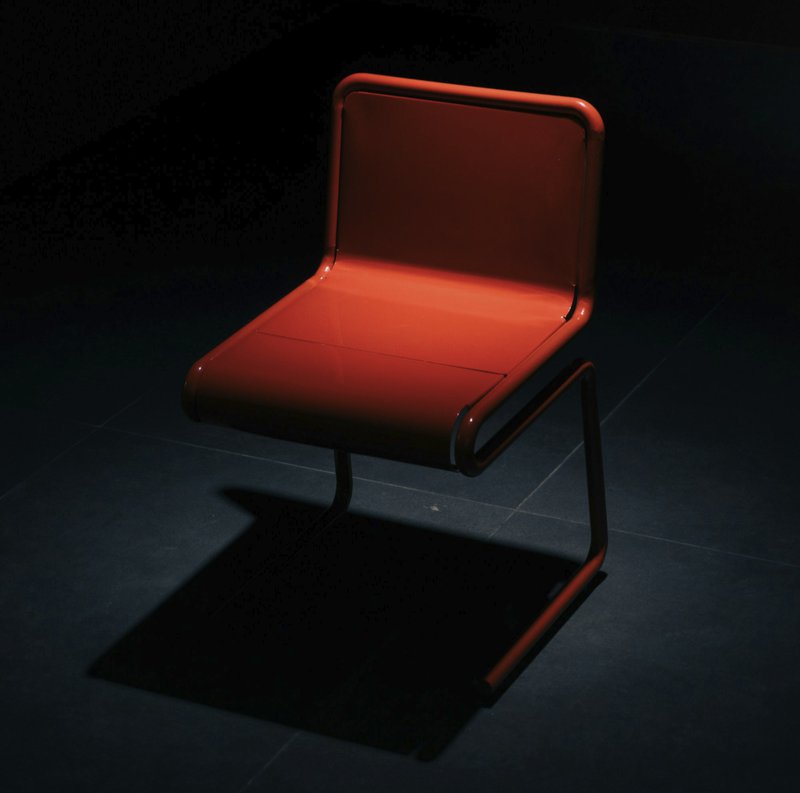 A single red chair in a dark room.