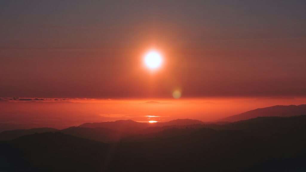 the sun is setting over a mountain range