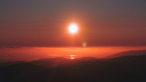 the sun is setting over a mountain range