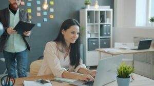 Woman working on laptop with man behind her