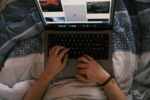a person typing on a laptop on a bed