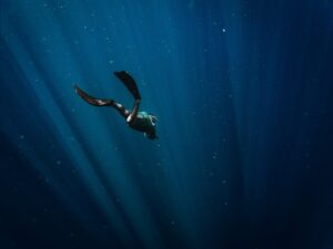 man in black wetsuit swimming in blue water
