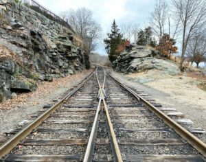 brown metal train rail near rocky mountain during daytime