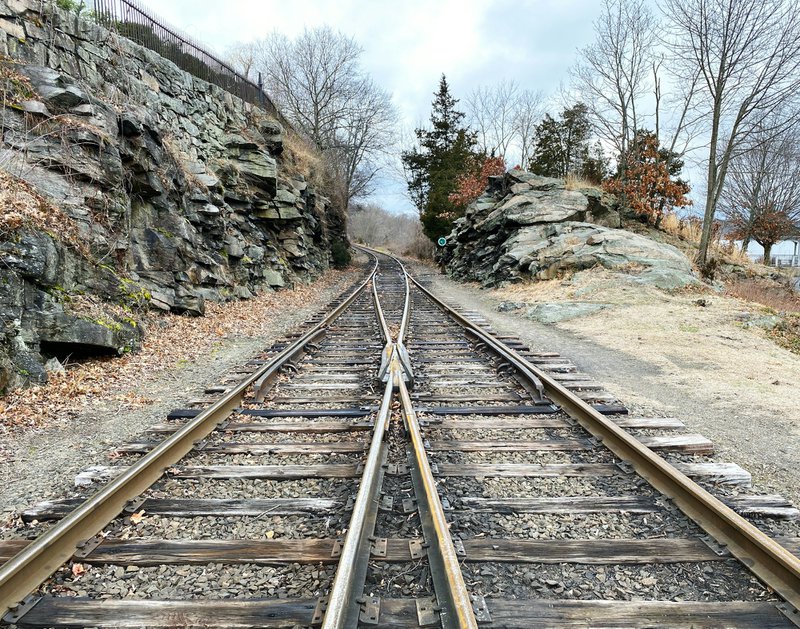 brown metal train rail near rocky mountain during daytime