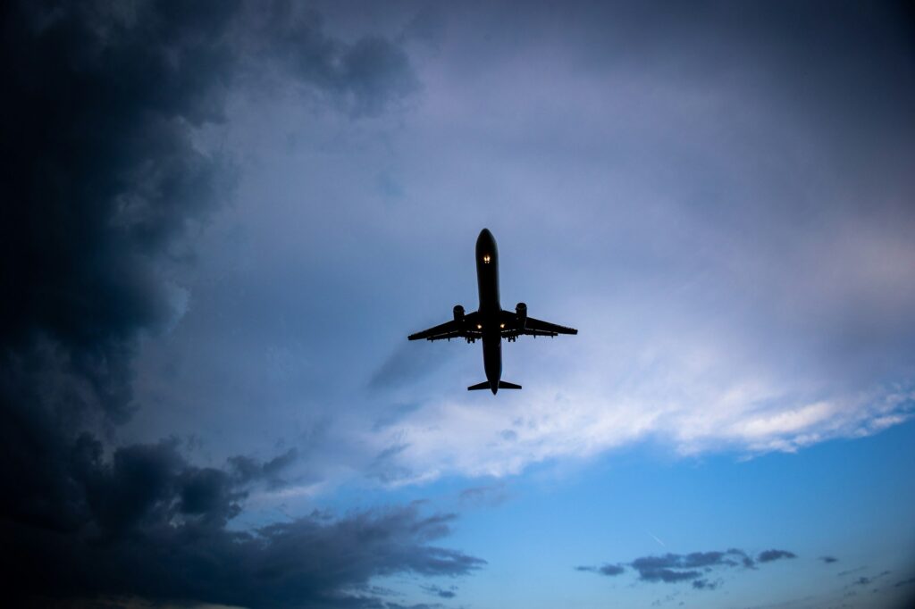 a plane flying in the sky with a cloudy background