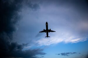 a plane flying in the sky with a cloudy background
