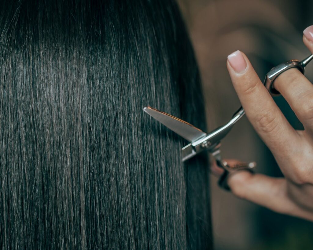 a woman is cutting her hair with scissors