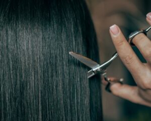 a woman is cutting her hair with scissors
