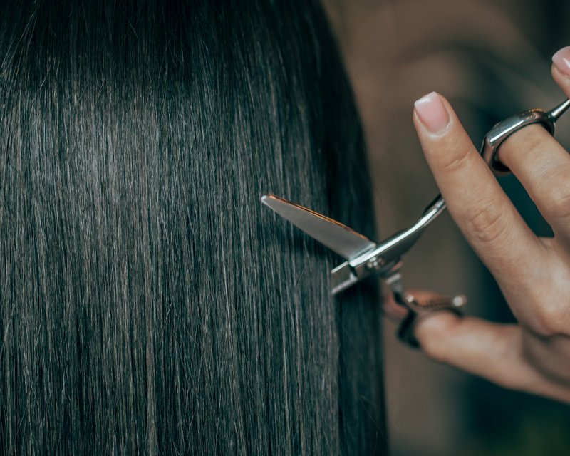 a woman is cutting her hair with scissors