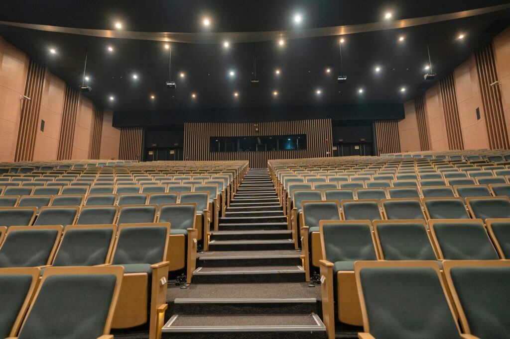 Empty theater seats with a central aisle and stage.