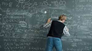 Student writing complex equations on a chalkboard