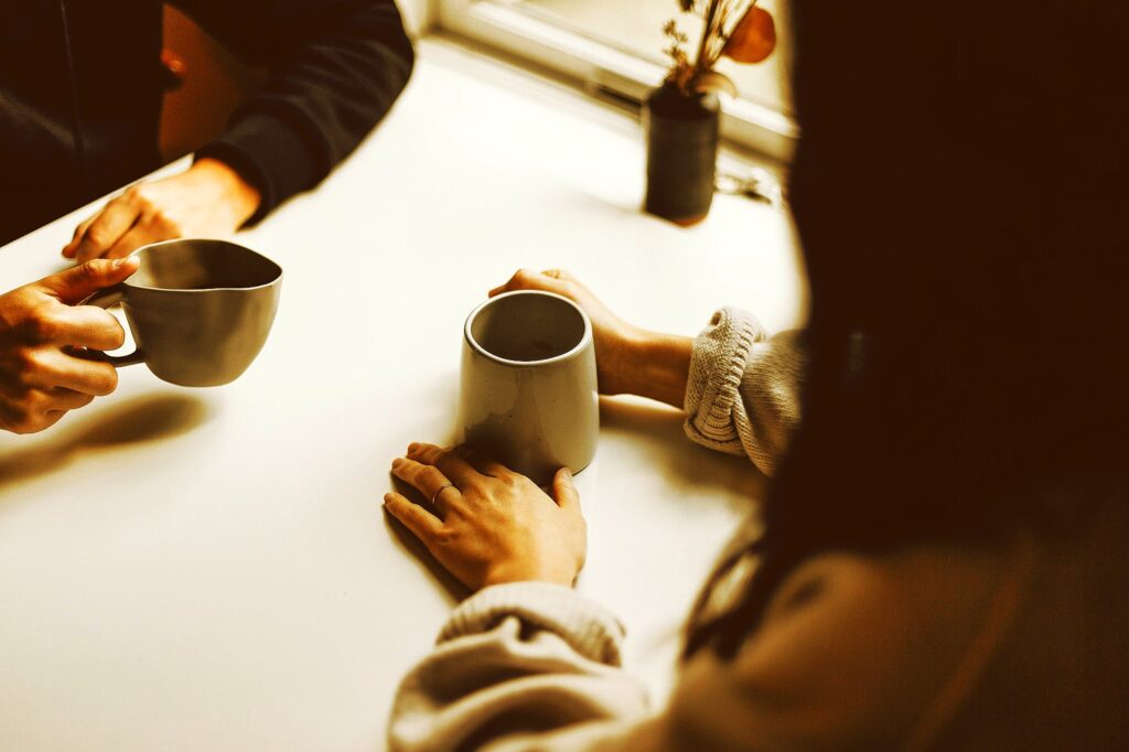 two people holding gray mugs at table