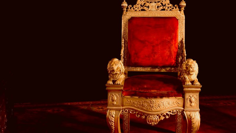 A gold and red chair sitting on top of a wooden floor