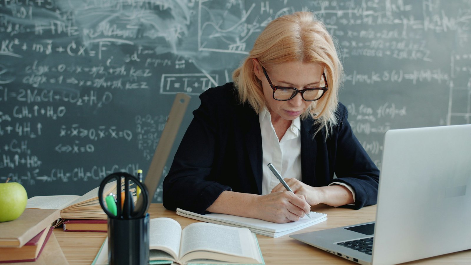 A woman writing in a notebook at a desk