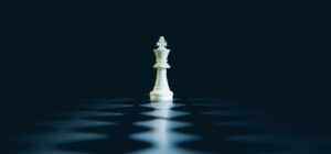 A single white chess king stands on a dark board