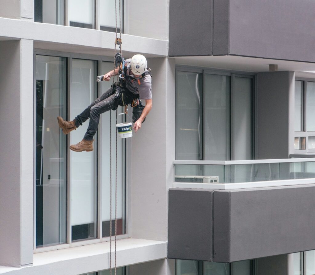 man in black jacket and black pants jumping on window during daytime