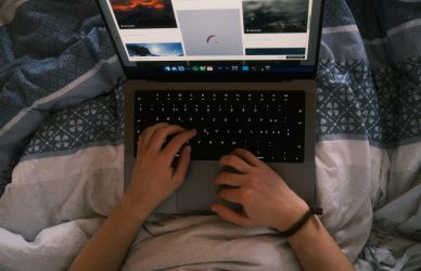 a person typing on a laptop on a bed