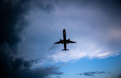 a plane flying in the sky with a cloudy background
