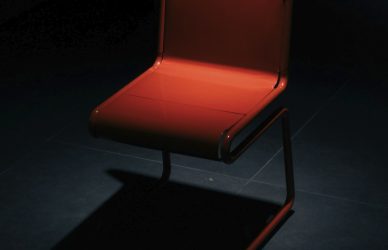 A single red chair in a dark room.