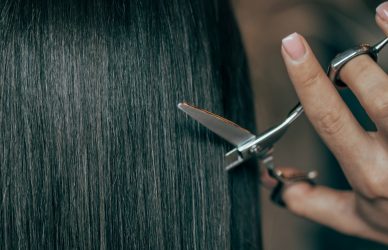 a woman is cutting her hair with scissors