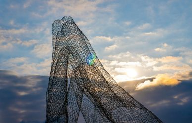 Abstract sculpture stands against a cloudy sky.