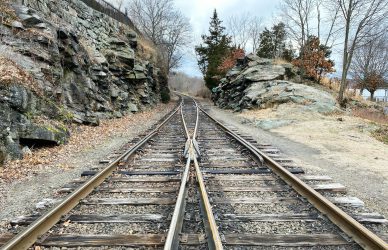brown metal train rail near rocky mountain during daytime