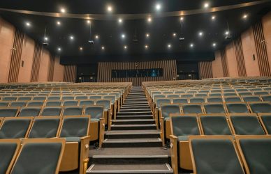 Empty theater seats with a central aisle and stage.