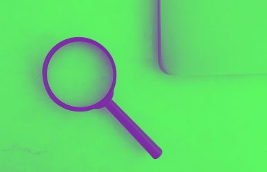 Magnifying glass sits near a laptop on a table.