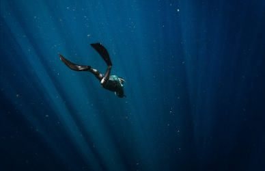 man in black wetsuit swimming in blue water
