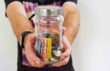 person holding clear glass jar filled with money