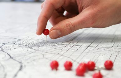 person placing red pin on city map