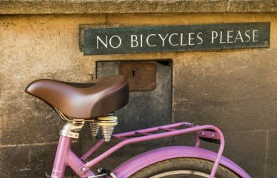 pink bicycle parked beside brown concrete wall