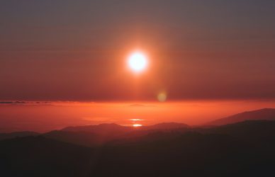 the sun is setting over a mountain range